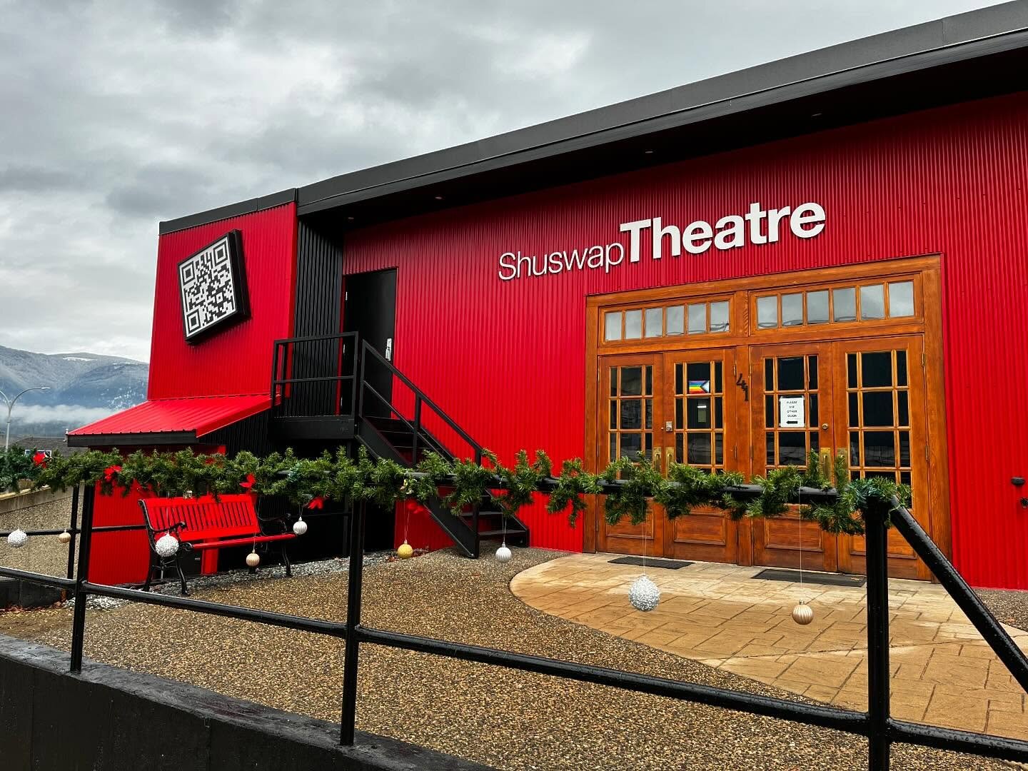 The Shuswap Theatre building seen from Hudson Avenue — a red corrugated facade with the Shuswap Theatre sign above wooden entrance doors.