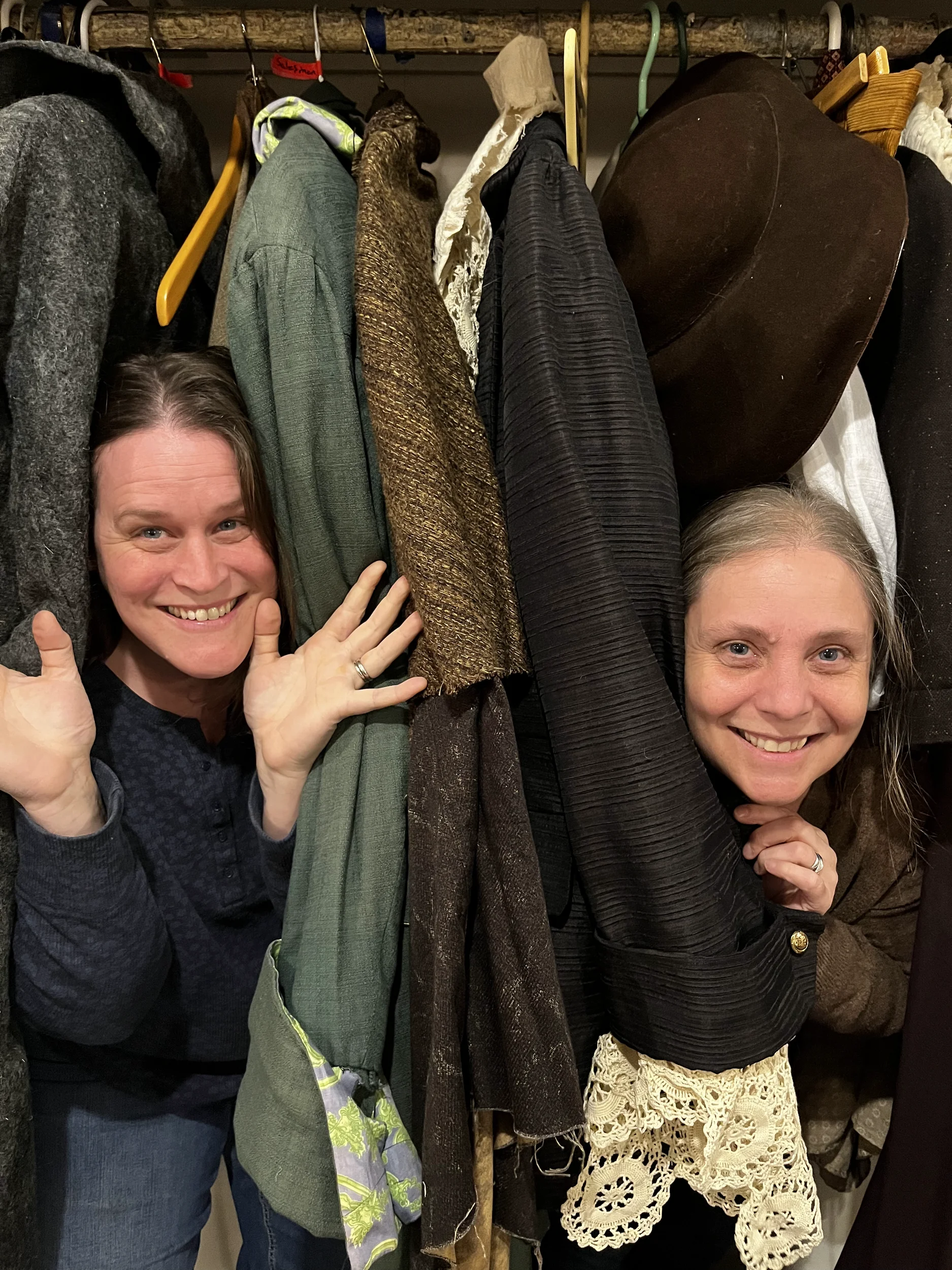 Two volunteers laughing among the costume racks backstage at Shuswap Theatre.